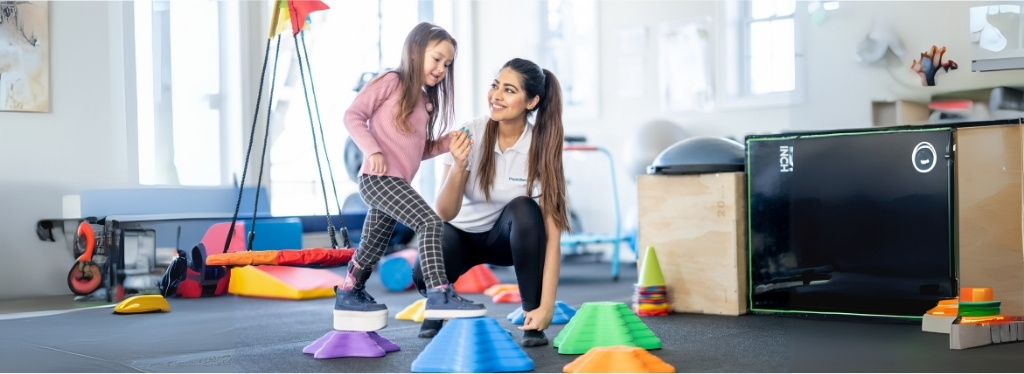 a person and a child playing with cones in a gym