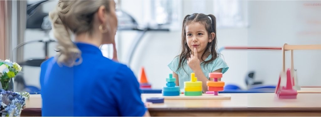 A child sitting at a table with a teacher