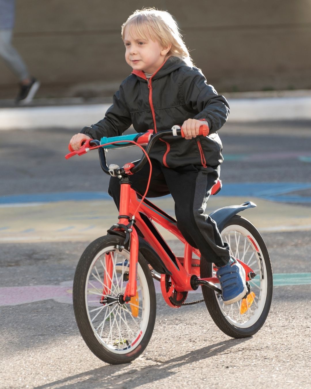 a boy riding a red bike in a parking lot