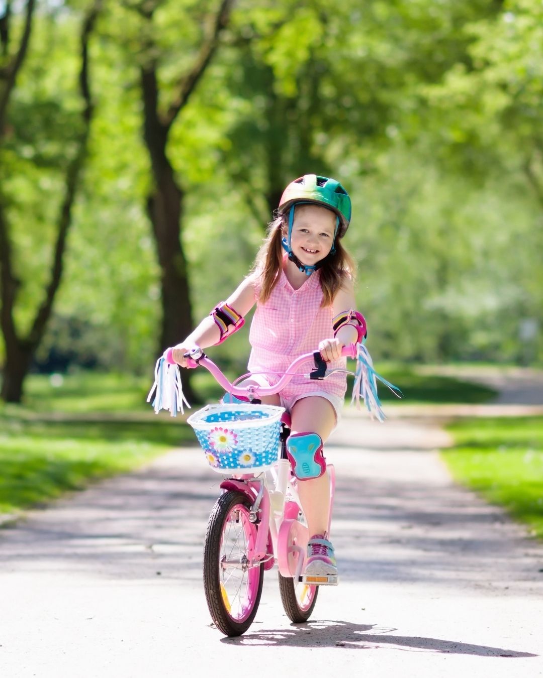 a child riding a pink bike down a path